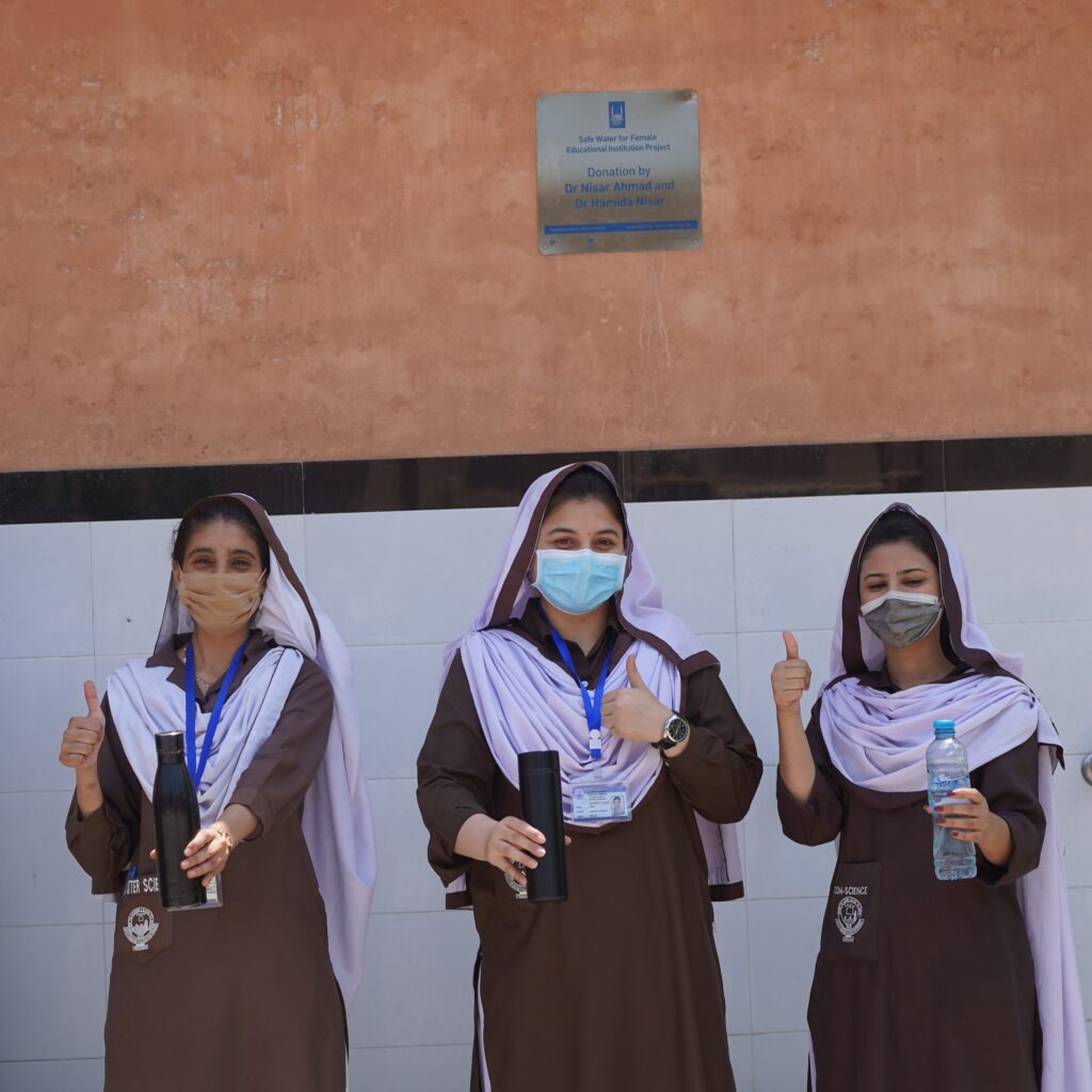 Students holding bottles filled with water from safe drinking taps for Safe Water for Female Educational Institution Project