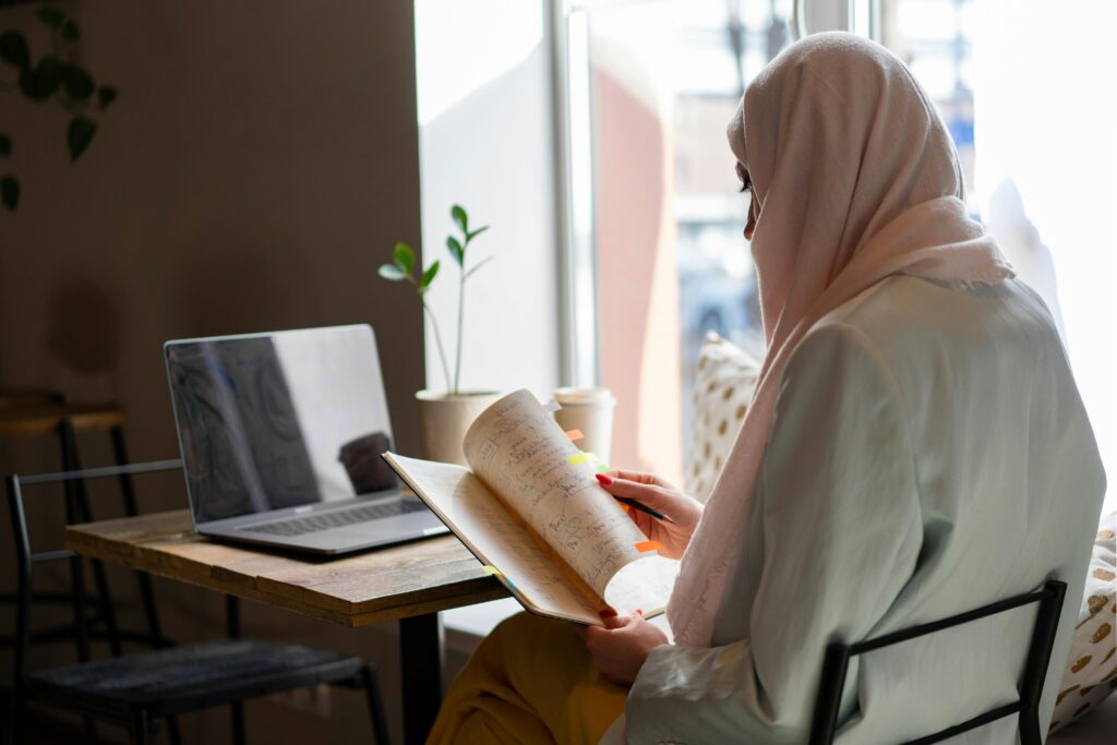 Muslimah (muslim woman) with books with notes, balancing study/work in Ramadan