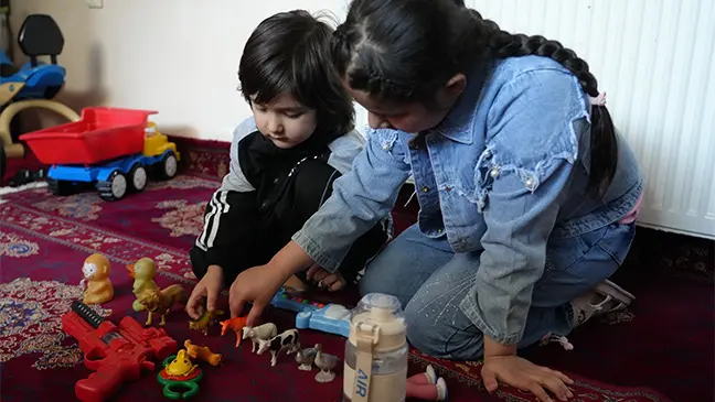 Maryam and her younger brother play with toys bought with Eid Gift cash assistance, in their home in Kabul, Afghanistan