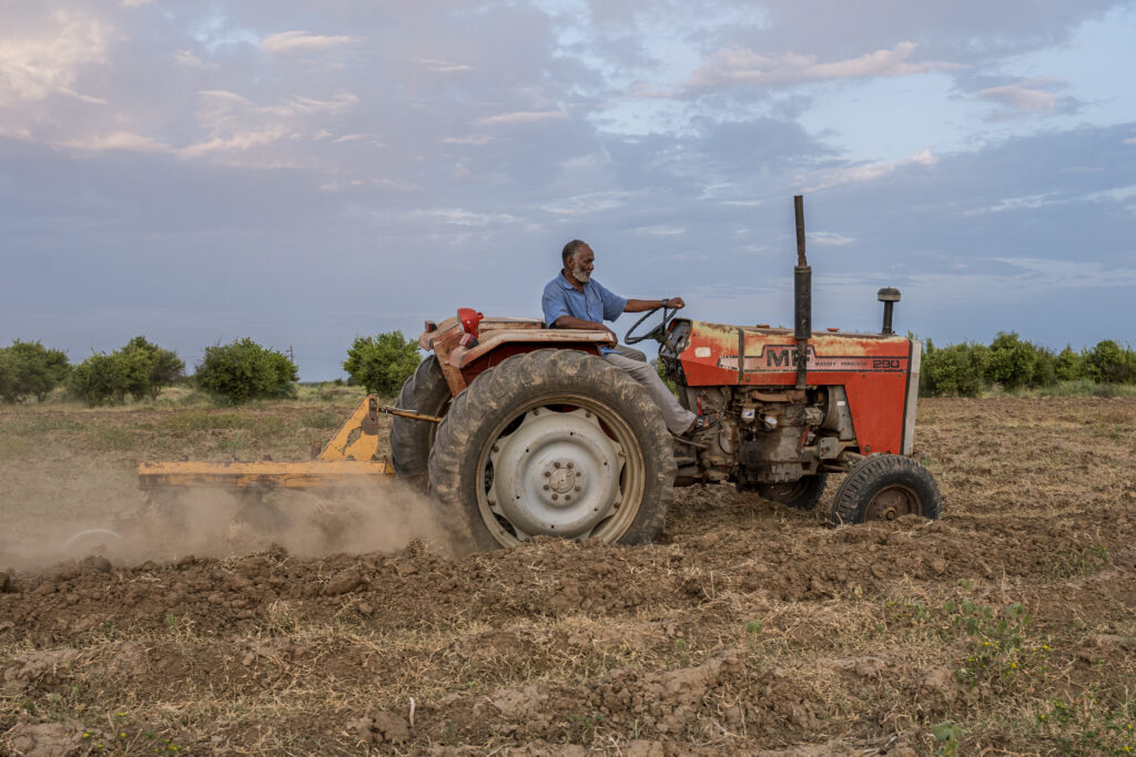 Sudanese farmer Ahmed on his tractor ploughing land for crops